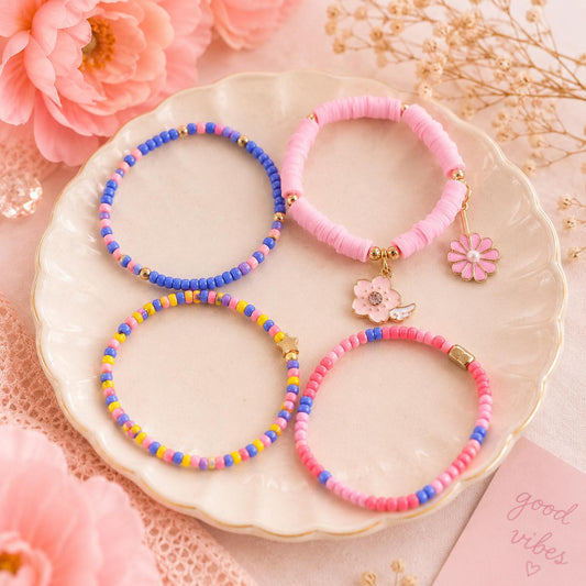 Four beaded stretch bracelets The bracelets include blue, yellow, pink beads, and 2 pink flower charms with gold-tone hardware.