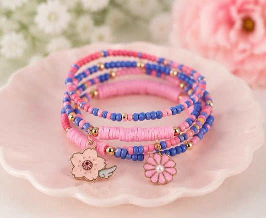 A set of pink and blue beaded wrap bracelets with gold-tone spacer beads and two dangling flower charms.